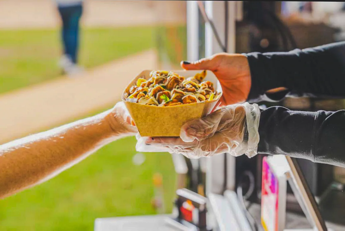 A Punjabi Bytes food order being handed to a customer at the Slacks Creek trailer
